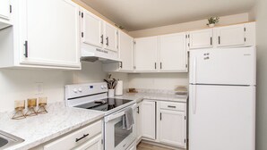 A modern kitchen with white cabinets, a built-in oven, a refrigerator, and a marble countertop. - Walk to DT I King I Keyless Entry I Garage I W/D (Fargo)