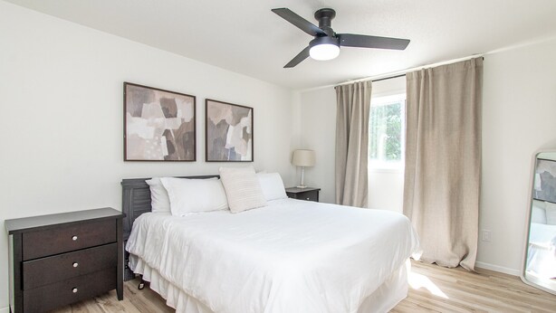 A bedroom with a bed, a nightstand, a lamp, a ceiling fan, and two abstract paintings on the wall. - Walk to DT I King I Keyless Entry I Garage I W/D (Fargo)