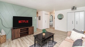 A living room with a TV displaying "NETFLIX," a wooden coffee table, a sofa, and a wardrobe. - Walk to DT I King I Keyless Entry I Garage I W/D (Fargo)