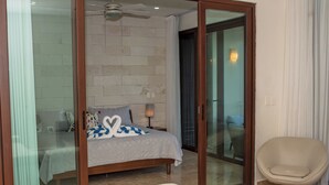Ein Schlafzimmer mit Bett, Stuhl und einer Schiebetür, die auf einen Balkon führt.