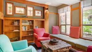 Un rincón acogedor para leer con una estantería de madera, un banco con cojines y una mesa de centro rústica.