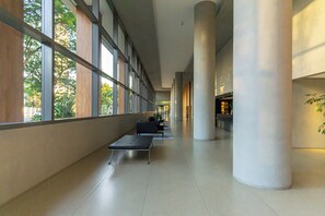 A corridor with large windows, a bench, and a potted plant. - Brooklin Fan - Comfort & Convenience (Cidade Monções São Paulo)