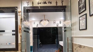 Una entrada de hotel moderna con puerta de vidrio, una araña y cuadros en la pared.