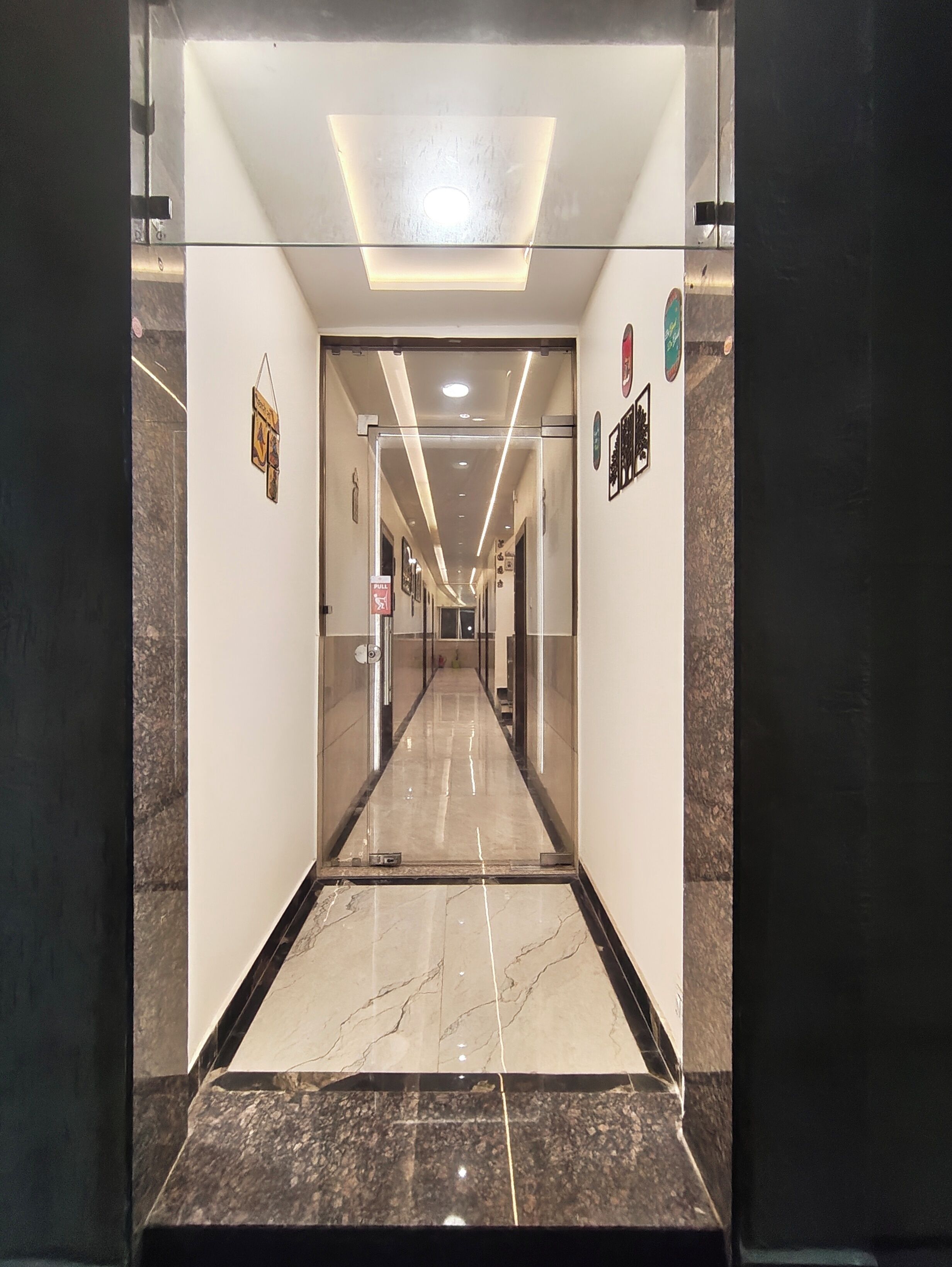 A hallway with a marble floor, a pull sign, and a door at the end.