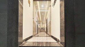 Un pasillo de hotel con piso de mármol, puertas de vidrio y un letrero que dice 'PULL'.