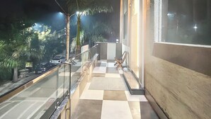 A balcony with a checkered floor, a railing, and a palm tree. - Taj Belleza Vista By Trippizo (Basai)