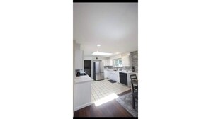 A modern kitchen with white cabinetry, a central island, and a large window providing natural light. - Charming villa with AC in Renton - perfect for large groups (Renton)