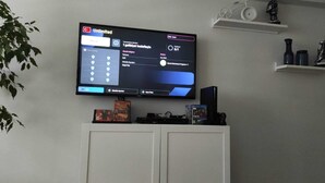Un téléviseur fixé au mur affiche une interface utilisateur proposant diverses options et paramètres.