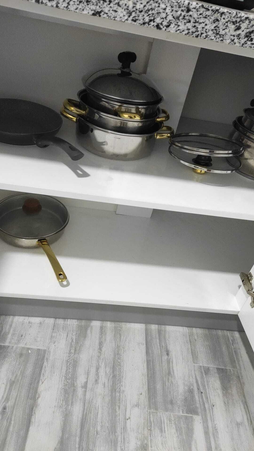 A kitchen with white countertops and grey wooden flooring.