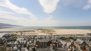 En kystby med historiske bygninger, en sandstrand og en parkeringsplads.
