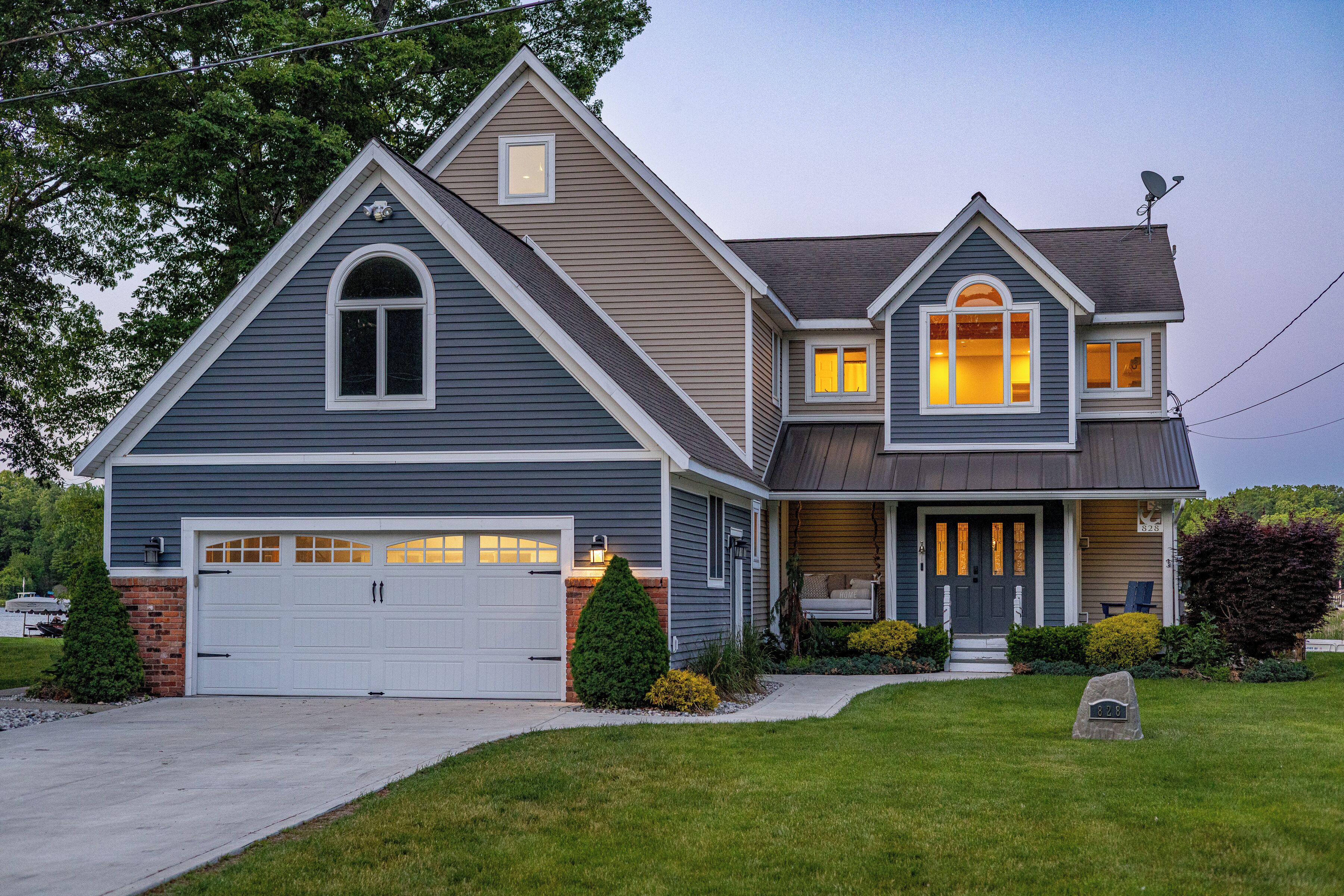 Une maison à deux étages avec un garage, un porche à l’avant et une pelouse bien entretenue.
