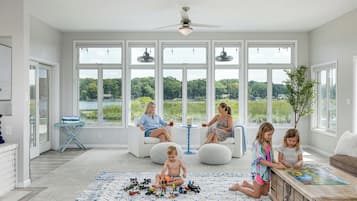 A spacious room with large windows, a ceiling fan, and a puzzle table.