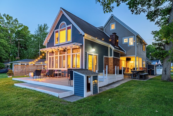 A two-story house with a covered patio, a small dog house, and a barbecue area.