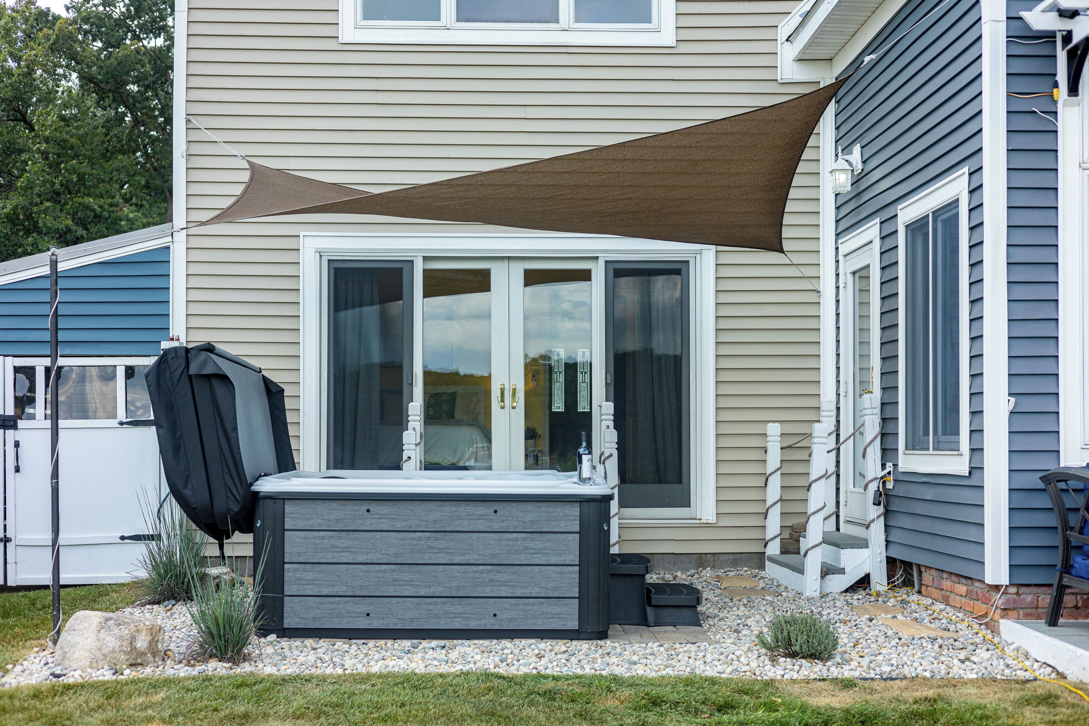 Een huis met een jacuzzi, een overdekt terras en een terras.
