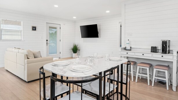 A modern kitchen with white cabinetry, a marble countertop, and a flat-screen TV mounted above the island. - The Beach Bungalow by Book That Condo (Panama City Beach)