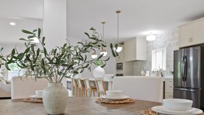 Una cocina moderna con una mesa de comedor de madera, platos blancos y un mantel tejido.