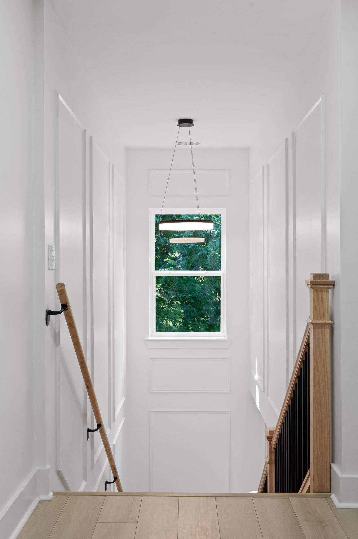 A white door with a window, a wooden handrail, and a light fixture above.