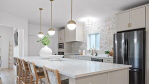 Una cocina moderna con una isla central, electrodomésticos de acero inoxidable y sillas de madera.