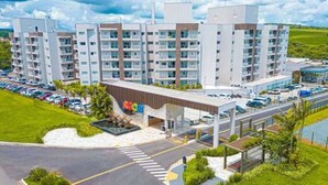 A modern multi-story hotel with a central atrium, parking area, and landscaped surroundings. - APARTMENT IN CALDAS NOVAS/LAGOA ECO TOWER RESORT... (Setor Lagoa Quente Caldas Novas)