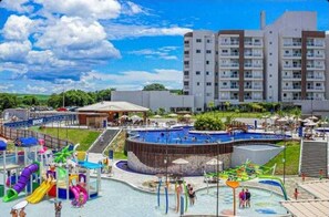A hotel with a swimming pool, water slides, and a parking area.