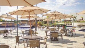 An outdoor patio area with round tables and chairs, surrounded by umbrellas. - APARTMENT IN CALDAS NOVAS/LAGOA ECO TOWER RESORT... (Setor Lagoa Quente Caldas Novas)