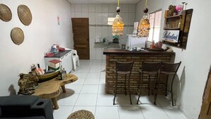A compact kitchen with a central island, a dining area with chairs, and a small table with decorative items. - Cozy house in Tutoia-Ma, close to everything, beaches, kite surfing, dunes. (Tutóia)