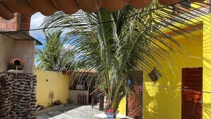 A narrow street with a yellow building, a palm tree, and a stone wall. - Cozy house in Tutoia-Ma, close to everything, beaches, kite surfing, dunes. (Tutóia)
