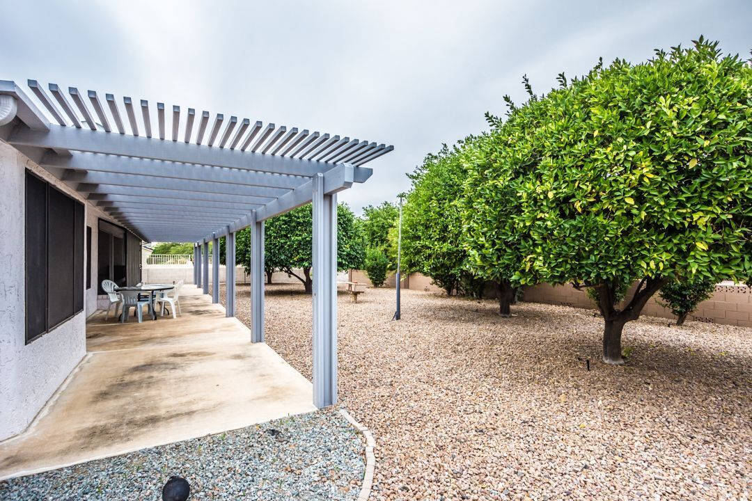A covered patio area with a concrete floor and a pergola structure.