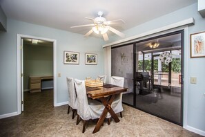 Un coin repas avec une table en bois, des chaises et un ventilateur de plafond.