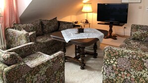 Un salon confortable avec un canapé, une table basse, un téléviseur et une lampe.