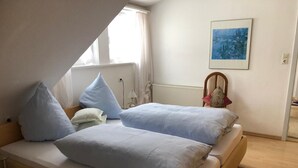 Une chambre avec deux lits, un radiateur, une fenêtre et un tableau accroché au mur.