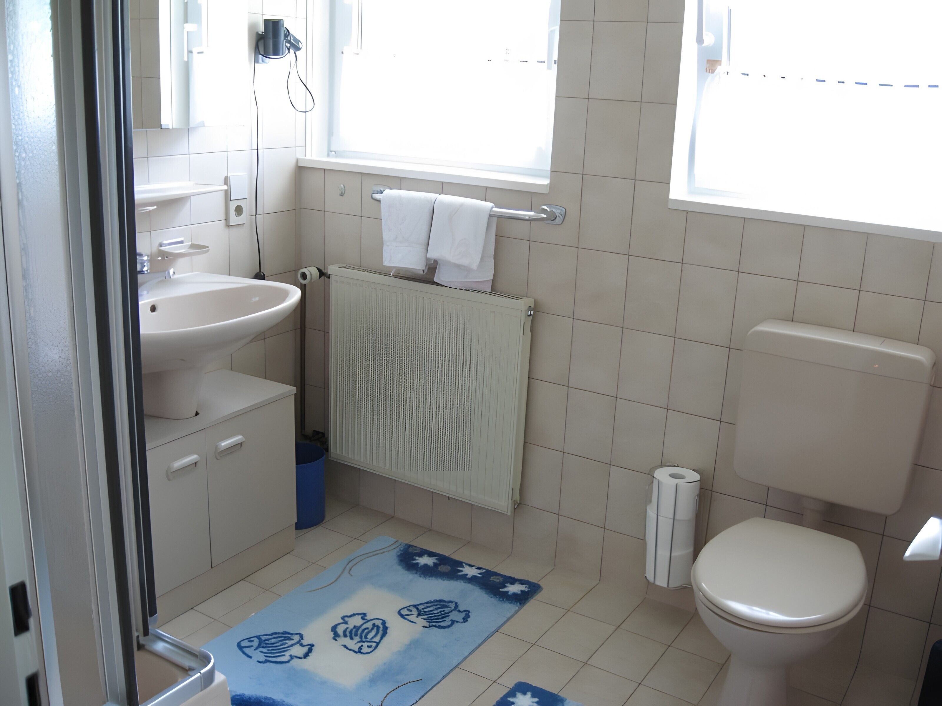 Une salle de bain avec un lavabo, des toilettes et une fenêtre.