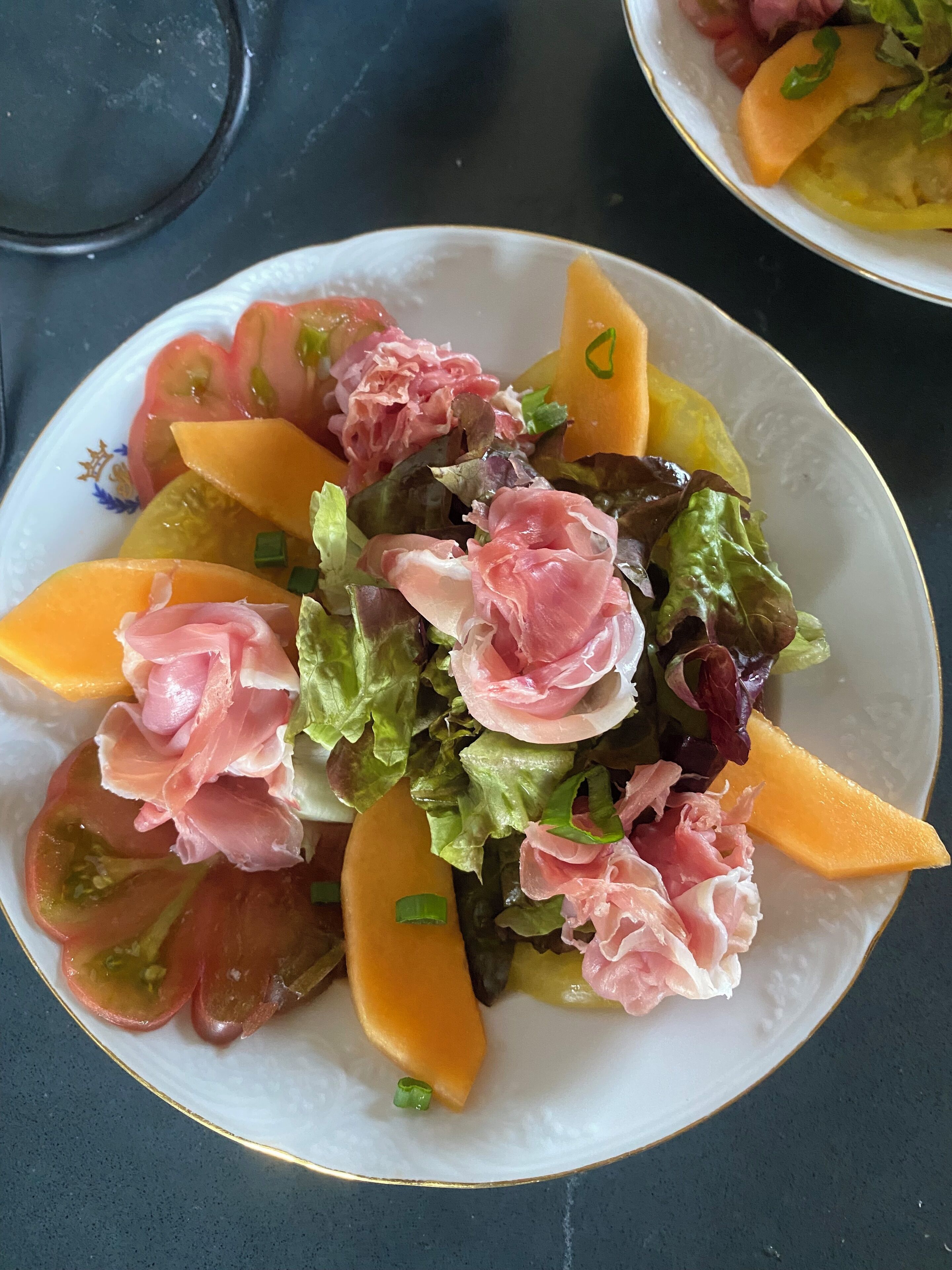 Un plato de ensalada mixta con diversos vegetales y lonchas de queso.