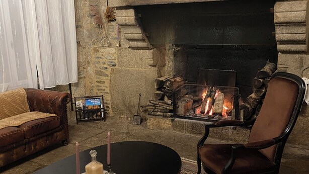 A cozy living room with a stone fireplace, a leather sofa, a wooden coffee table, and a patterned rug.