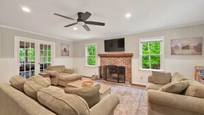 A living room with beige sofas, a fireplace, and a ceiling fan.