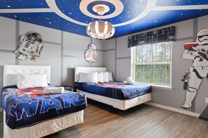 A bedroom with two beds, Star Wars-themed decor, a Star Wars helmet, and a Star Wars poster on the wall.