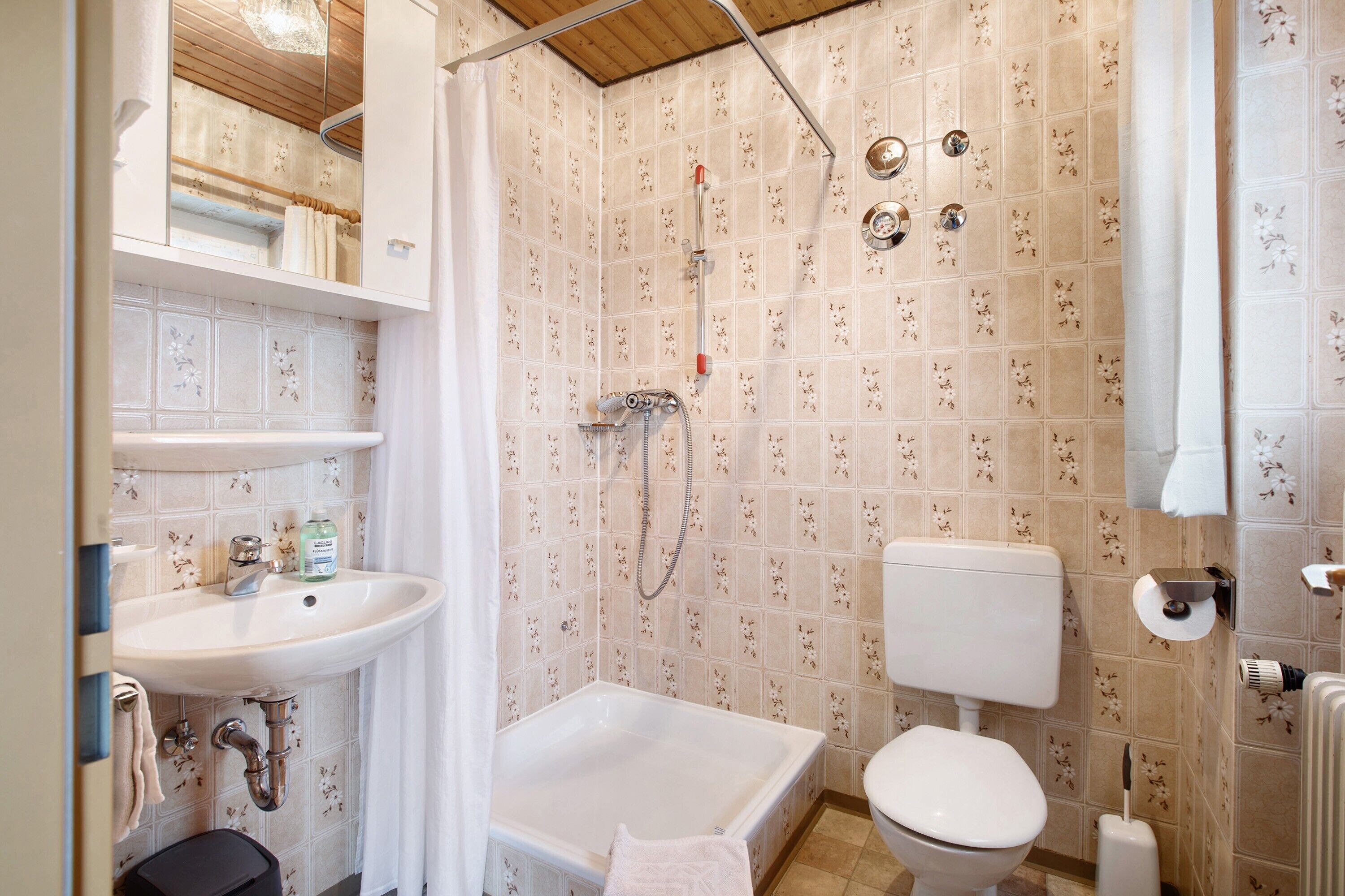 A bathroom with a shower, toilet, sink, and a mirror.