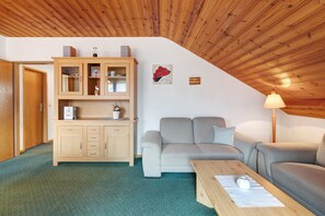 A cozy room with a wooden ceiling, a sofa, a cabinet, and a lamp.