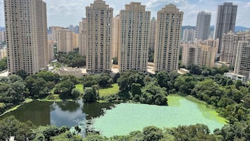 A high-rise residential building complex with multiple apartment buildings, surrounded by lush greenery and a small pond.