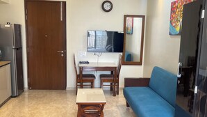 A compact living space with a kitchenette, a dining table, a sofa, and a mirror.