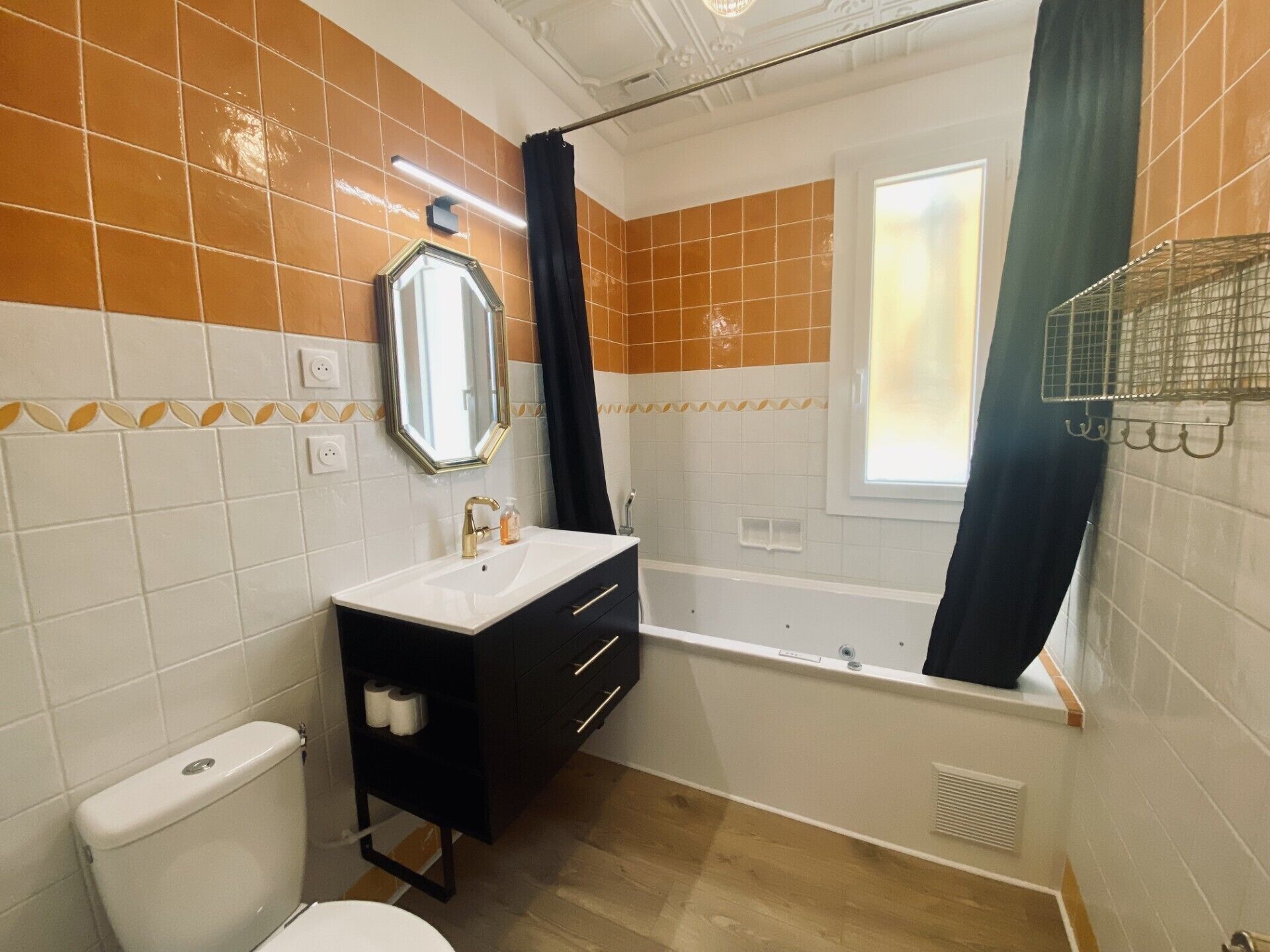 Une salle de bain comprenant des toilettes, un lavabo, un meuble-lavabo, une baignoire et une fenêtre.