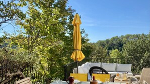 An outdoor dining area with a table set for a meal, surrounded by chairs and a yellow umbrella. - Family villa - Breathtaking view of the vineyards - private, fenced pool. (Entrecasteaux)