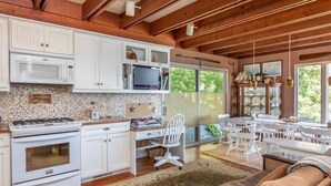 A spacious kitchen with white cabinets, a microwave, stove, and a dining area with white chairs and a table.