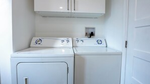 Un cuarto de lavandería con dos lavadoras de carga frontal y un armario arriba.