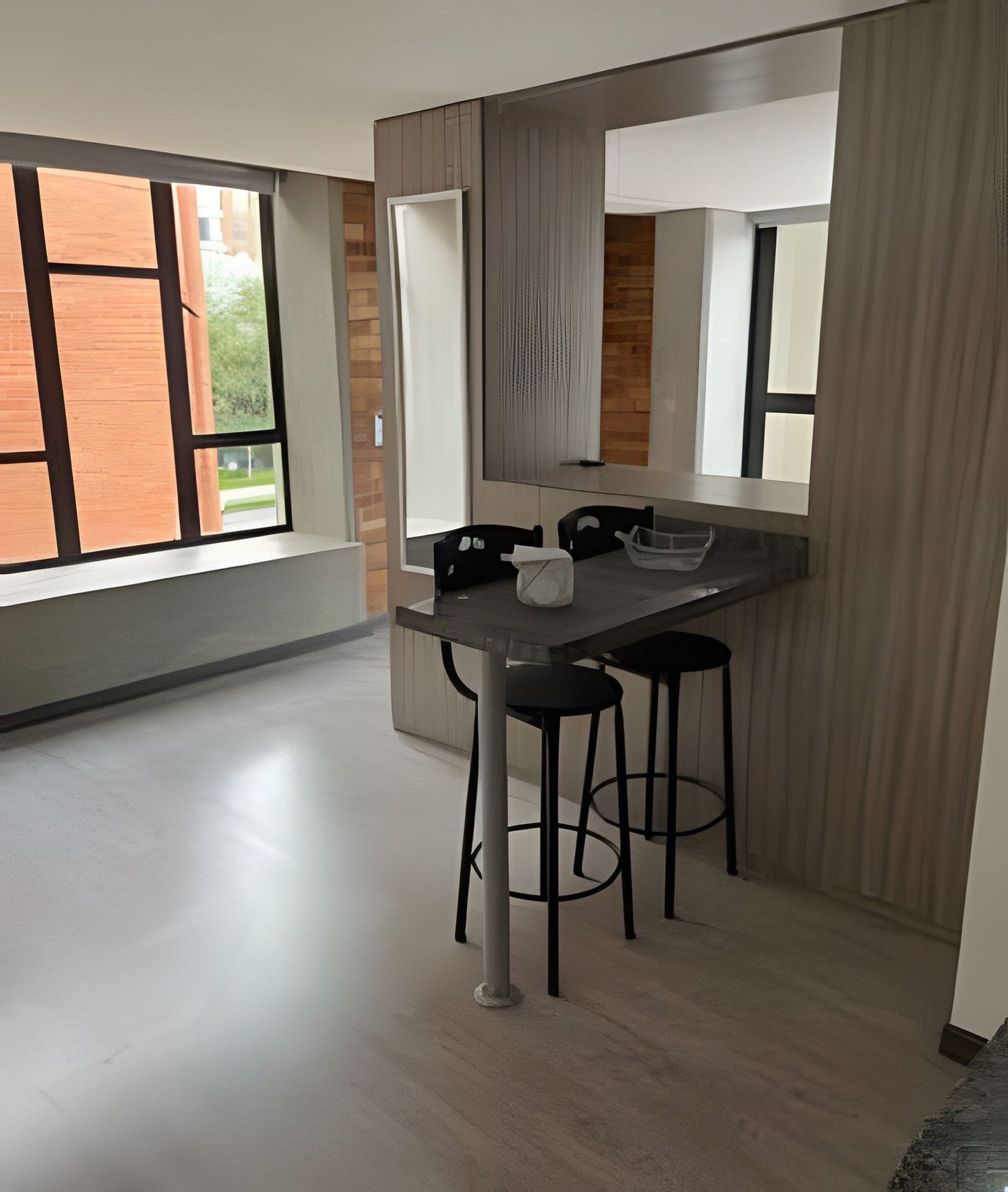 Een moderne keuken met een centraal kookeiland, zwarte barstoelen en grote ramen.