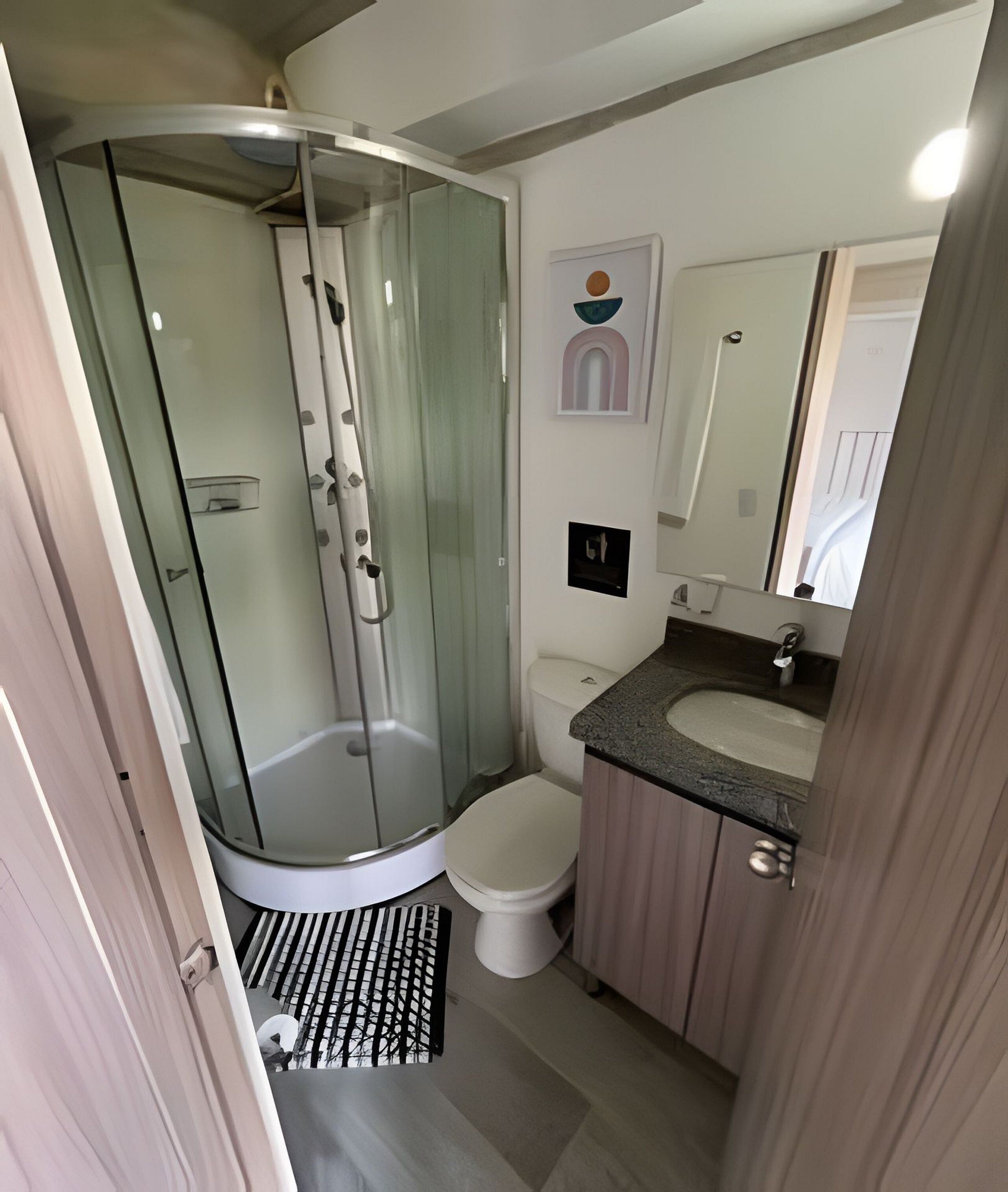 Een badkamer met een douchecabine, toilet, wastafel en spiegel.