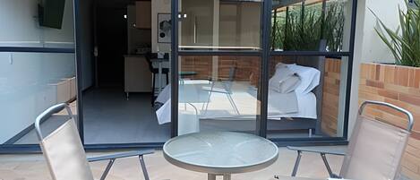Un patio con una puerta de vidrio que da a una habitación con una cama y una mesa.