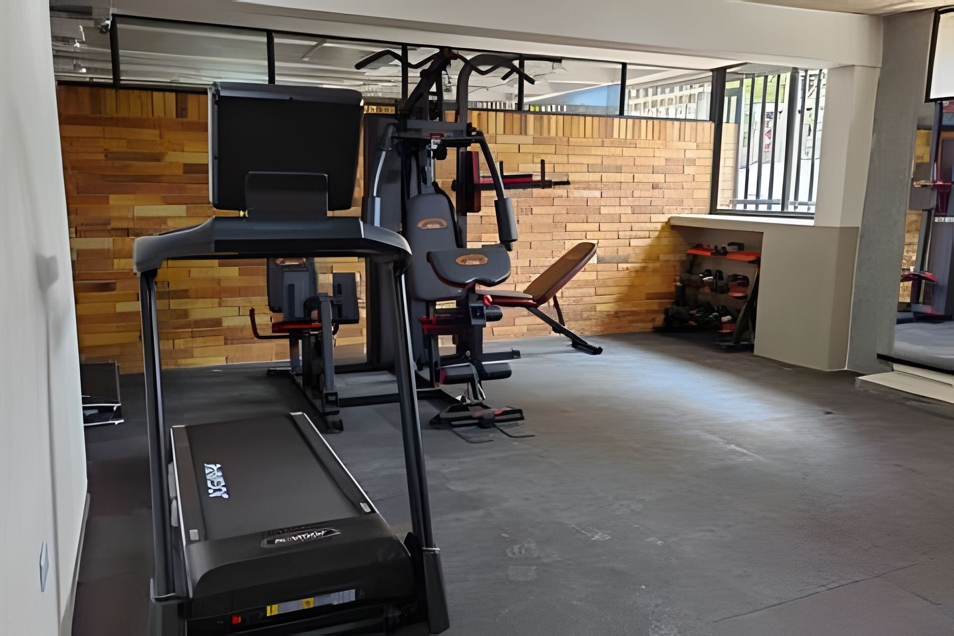 A gym with a treadmill, weight machines, and a bench.