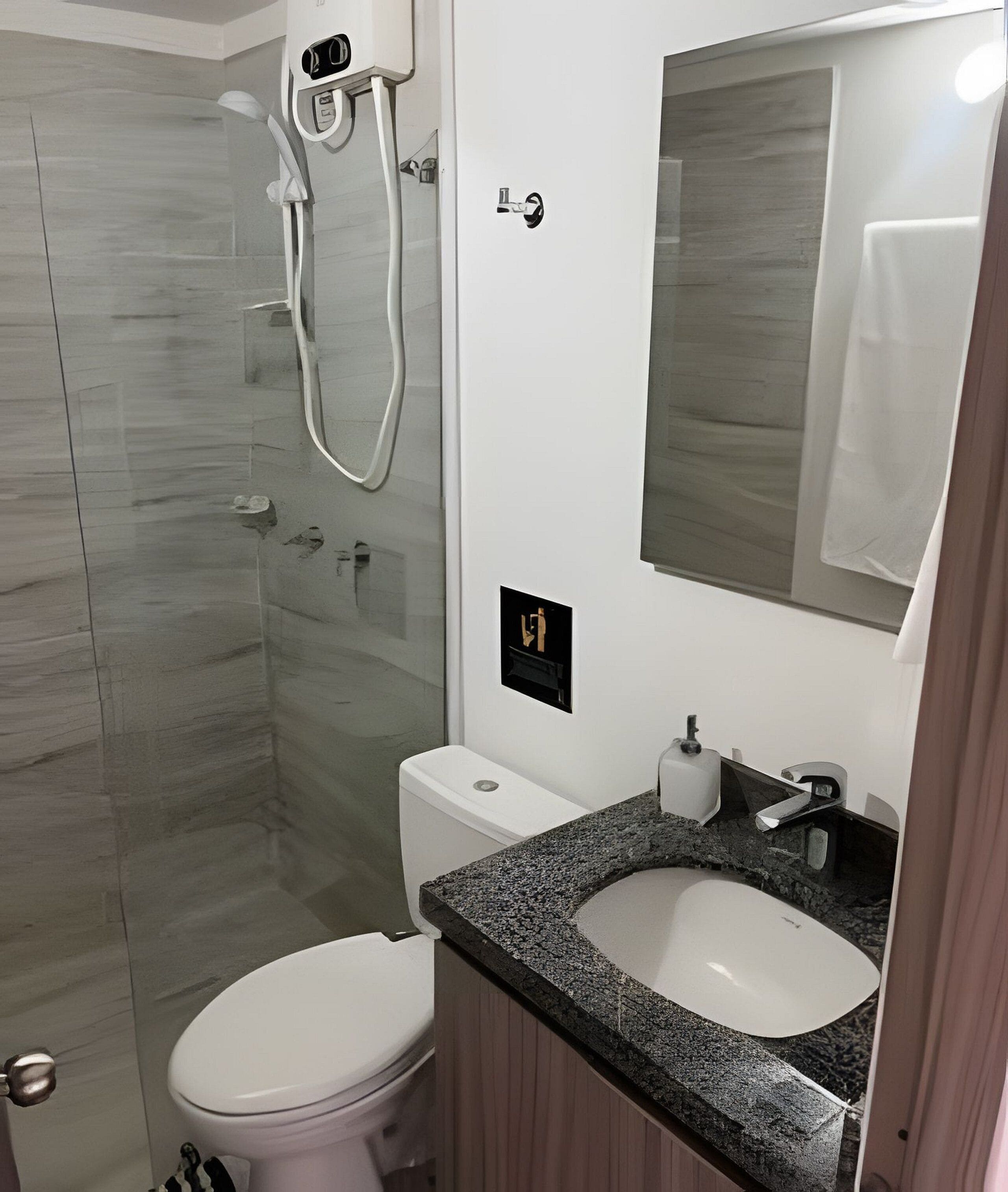A bathroom with a shower, toilet, sink, and mirror.