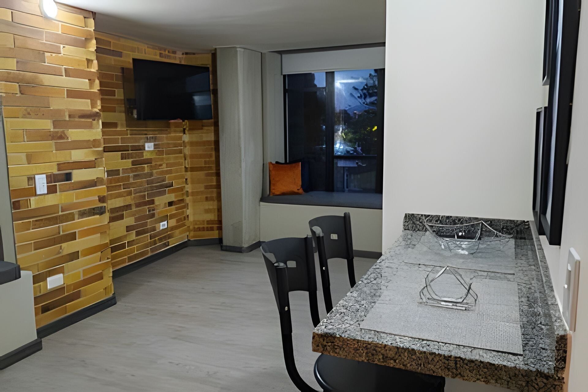 Une cuisine moderne avec un mur en briques, une fenêtre offrant une belle vue et un coin repas avec des chaises et une table.